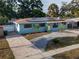 Eye-level view of a single-story home with solar panels, paved driveway, and vibrant landscaping at 4721 W Iowa Ave, Tampa, FL 33616