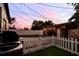Backyard at dusk featuring a well-manicured lawn, string lights, and a white picket fence at 4767 6Th N Ave, St Petersburg, FL 33713
