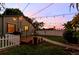 Backyard view at dusk, enhanced by charming string lights, a wood deck, and lush surroundings at 4767 6Th N Ave, St Petersburg, FL 33713