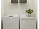Bright laundry room with white washer and dryer and storage shelves above at 5137 Benjamin Eric St, Zephyrhills, FL 33541