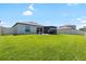 Spacious backyard featuring a well-maintained lawn, screened lanai with patio furniture, and a privacy fence at 5208 Dandelion St, Apollo Beach, FL 33572