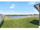 Beautiful backyard with a large green lawn and a serene lake view beyond the white picket fence at 5208 Dandelion St, Apollo Beach, FL 33572