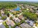 Neighborhood aerial view features lush trees, a nearby lake, and houses with pools and solar panels at 5216 Kernwood Ct, Palm Harbor, FL 34685