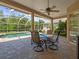 Covered patio with brick flooring, a ceiling fan, and a table perfect for outdoor dining next to the pool at 5216 Kernwood Ct, Palm Harbor, FL 34685