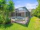 The screened-in pool features an attached jacuzzi, along with greenery for a private outdoor getaway at 5216 Kernwood Ct, Palm Harbor, FL 34685