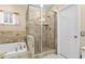 Bright bathroom featuring a glass enclosed shower, tiled walls, and soaking tub with decorative accents at 5520 Terrain De Golf Dr, Lutz, FL 33558