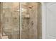 Up-close view of an updated bathroom with a glass enclosed shower, tiled walls, and shelves at 5520 Terrain De Golf Dr, Lutz, FL 33558