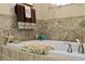 Close-up shot of a soaking tub with tiled walls and decor; ideal for relaxation and spa days at home at 5520 Terrain De Golf Dr, Lutz, FL 33558