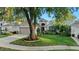 Charming home exterior with a well-maintained lawn, mature tree, and a two-car garage at 5520 Terrain De Golf Dr, Lutz, FL 33558
