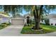 Charming home exterior with a well-maintained lawn, mature tree, and a two-car garage at 5520 Terrain De Golf Dr, Lutz, FL 33558