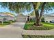 Well-maintained single-story home featuring manicured landscaping and a two-car garage, with a beautiful tree in the front yard at 5520 Terrain De Golf Dr, Lutz, FL 33558