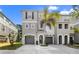 Three-story townhome featuring a gray facade, arched entryway, and a well-maintained driveway with landscaping at 616 Wheaton Trent Pl, Tampa, FL 33619