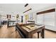 Open-concept living room with a billiards table, hardwood floors, and modern lighting fixtures, adjacent to the kitchen at 616 Wheaton Trent Pl, Tampa, FL 33619
