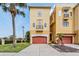 Charming three-story home with a terracotta garage door, balcony, and well-manicured lawn with a palm tree at 6404 Mayra Shores Ln, Apollo Beach, FL 33572