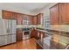 Well-lit kitchen featuring stainless steel appliances, wood cabinets, granite countertops, and stylish backsplash at 6404 Mayra Shores Ln, Apollo Beach, FL 33572