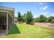 Lush backyard showcasing green grass, mature trees, and a screened-in porch for enjoying the serene outdoor space at 8712 Ashbury Dr, Hudson, FL 34667