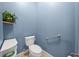 Powder room featuring blue walls, a modern toilet, a convenient grab bar, and a decorative plant shelf at 10117 Breezy Pines Ct, Weeki Wachee, FL 34613
