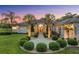 Elegant home featuring manicured landscaping, a circular driveway, and a covered entryway, set against a colorful dusk sky at 10117 Breezy Pines Ct, Weeki Wachee, FL 34613
