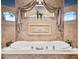 Close up of main bathroom's soaking tub adorned with artwork and a small window at 10117 Breezy Pines Ct, Weeki Wachee, FL 34613