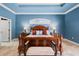 Spacious main bedroom features a wooden bed frame, blue walls, and a tray ceiling at 10117 Breezy Pines Ct, Weeki Wachee, FL 34613