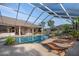 Enclosed pool with spa, waterfall feature, plants, brick pavers and modern furniture at 10117 Breezy Pines Ct, Weeki Wachee, FL 34613