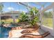 Pool with rock waterfall feature, tropical plants and wood lounge chairs at 10117 Breezy Pines Ct, Weeki Wachee, FL 34613