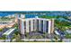 Aerial view of a tall condominium complex surrounded by waterfront views and lush landscaping at 10355 Paradise Blvd # 413, Treasure Island, FL 33706