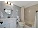 Bathroom featuring a white vanity, round mirror, toilet and shower with white tile at 10355 Paradise Blvd # 413, Treasure Island, FL 33706