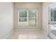 An empty room with neutral walls, tile floors, and a window overlooking a green space at 1177 Emerald Hill Way, Valrico, FL 33594