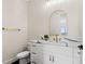 Elegant powder room with a marble countertop, white cabinetry, gold fixtures, and a modern arched mirror at 121 E Warren Ave # 1, Tampa, FL 33602