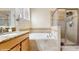 Well-lit bathroom featuring a soaking tub, walk-in shower, and granite countertop vanity at 13414 Graham Yarden Dr, Riverview, FL 33579
