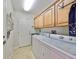 Bright laundry room featuring a white washer and dryer, wooden cabinets, and diamond pattern tile flooring at 1348 Emerald Dunes Dr, Sun City Center, FL 33573