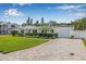 Charming single-story home with lush green lawn, manicured hedges, and a paved driveway leading to a garage at 1404 84Th N Ave, St Petersburg, FL 33702