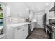 A modern kitchen featuring white cabinetry, stainless steel appliances, and gray backsplash at 1404 84Th N Ave, St Petersburg, FL 33702