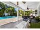 A covered patio featuring ceiling fans, an outdoor kitchen, and a dining table that overlooks the pool at 1404 84Th N Ave, St Petersburg, FL 33702