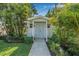 A detached, light-blue shed features a stone path, double doors, and is surrounded by lush landscaping at 1404 84Th N Ave, St Petersburg, FL 33702