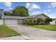 Charming single-story home with a well-manicured lawn and a long driveway leading to the garage at 1812 Teakwood Ln, Dunedin, FL 34698