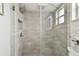 Standing shower features gray tiling, glass divider, rainfall shower head, and shower caddy at 1812 Teakwood Ln, Dunedin, FL 34698