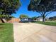 Wide concrete driveway leading to a charming light blue home, surrounded by mature trees at 1818 Douglas Ave, Dunedin, FL 34698