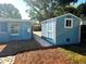 Exterior shot of blue shed with adjacent house featuring well-maintained lawn, adding curb appeal at 1818 Douglas Ave, Dunedin, FL 34698