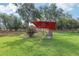 Expansive backyard with mature trees, lush lawn, and a relaxing lounge area under a shaded umbrella at 20254 Ravens End Dr, Tampa, FL 33647