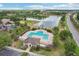 Aerial view of a resort-style community pool with ample lounge chairs and a covered pavilion next to a serene lake at 20254 Ravens End Dr, Tampa, FL 33647