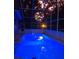 Screened-in pool with underwater lighting and lush surroundings at dusk at 2042 Craft Ln, Sarasota, FL 34239