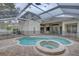 Screened-in pool and spa featuring brick pavers and a safety fence, with access to the home's sliding glass doors at 21215 Tyrell Way, Land O Lakes, FL 34638