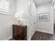 Hallway featuring wood floors, a decorative cabinet with lamp, artwork, and closet space at 214 S Audubon Ave, Tampa, FL 33609
