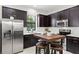 A modern kitchen featuring stainless steel appliances, dark wood cabinets, and a breakfast table at 214 S Audubon Ave, Tampa, FL 33609