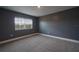 A grey painted bedroom with carpet flooring has a window and white trim around the baseboards at 219 Galaxy Ave, Spring Hill, FL 34606