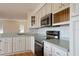 Well-lit kitchen with white cabinets, stainless steel appliances, and wood flooring at 219 Galaxy Ave, Spring Hill, FL 34606