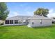 This backyard features a covered patio and large, green grass lawn under a blue sky at 2203 Malaga Ave, Spring Hill, FL 34609