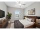 Bedroom features a wood bed, natural light from the window and a TV, creating a cozy and modern space at 31970 Blue Passing Loop, Wesley Chapel, FL 33545